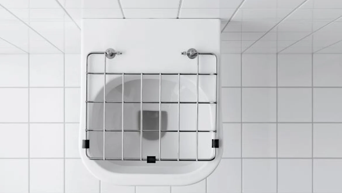 Vidoir Geberit Publica avec grille, installé dans un local carrelé.